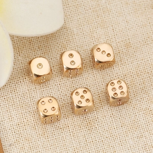 Lot de six perles dés en laiton or rose pour bijoux DIY sur fond en lin rustique chic