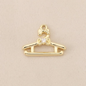 Detail van 18K vergulde hanger in kledinghanger-vorm met strik en zirkoon voor DIY-sieraden