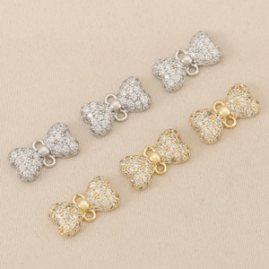 Macro view of micro-pave bow pendants with gold and silver finish for DIY jewelry