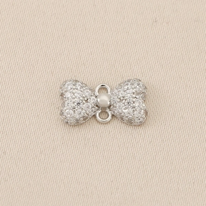 Macro detail of a silver bow pendant with micro-pave cubic zirconia for DIY jewelry