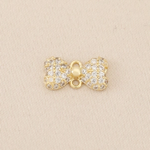 Macro detail of gold-plated bow charm with micro-pave cubic zirconia and double loops