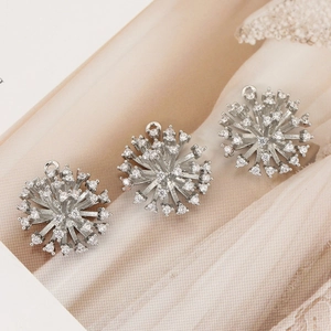 Three silver starburst pendants with micro-pave cubic zirconia on magazine background