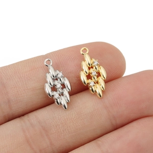 Macro shot of leaf pendant with three small zircons on a fingertip for DIY jewelry