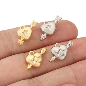 Primo piano di ciondoli a cuore placcati oro 18k con frecce e zirconi brillanti incastonati
