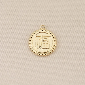 Detailed macro view of an 18K gold-plated circular charm with an embossed Chinese Fu character
