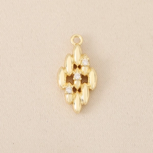 Macro detail of gold rhombus pendant with three inlaid zircons for DIY jewelry making
