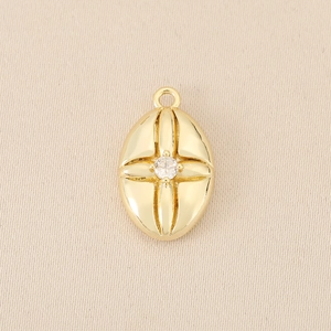 Macro shot of 18K gold plated oval pendant with cross pattern and center zircon stone