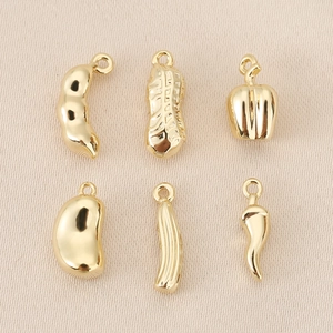 Macro detail of 18K gold plated vegetable charms including peanut and chili pendants