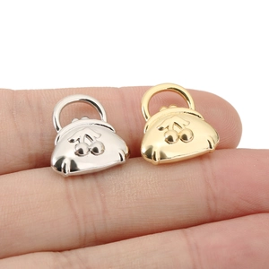 Macro shot of 18K gold and silver cherry handbag pendants on fingertips for size
