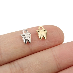 Macro shot of gold and silver smiling tooth charms for DIY jewelry making accessories