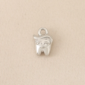Detailed macro view of a polished silver tooth charm with smiling face and golden hair