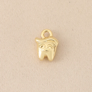 Macro shot of 18K gold plated tooth pendant with a smiling face for DIY jewelry