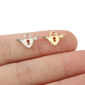 Macro view of gold and silver heart lock charms with wings for DIY jewelry making
