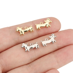 Vue macro de petits pendentifs teckel en or et argent 18K sur le bout d'un doigt
