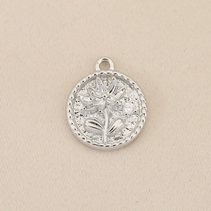 Detailed relief flower round pendant with cubic zirconia on textured metal surface