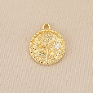 Macro view of gold round pendant featuring lotus relief and small white zircon inlay
