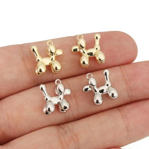 Miniature balloon dog charms in gold and silver held on fingers to show actual small size