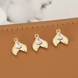 Golden mermaid tail charms with zircon inlay for DIY jewelry making on leather background