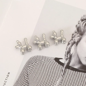 Three silver balloon dog charms on a fashion magazine for DIY jewelry making