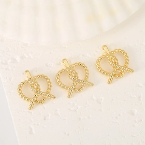 Pendentif bretzel plaqué or 14K pour création de bijoux DIY sur marbre blanc chic