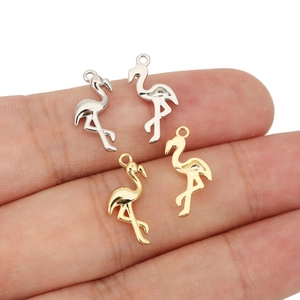 Macro shot of 18k gold and silver flamingo charms for DIY jewelry making on fingertips