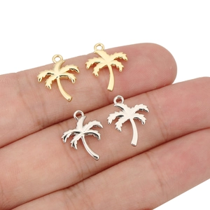 Macro view of gold and silver palm tree charms held by hand to show compact size and finish