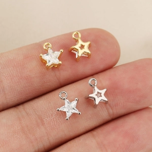 Miniature 18k gold star charm with zircon on fingertip showing its tiny size for DIY jewelry