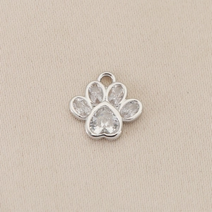 Macro view of 18K gold-plated silver paw print pendant with clear heart-shaped crystals