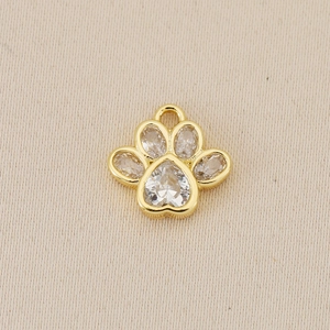 Detailed macro view of 18K gold paw print pendant with sparkling heart-shaped zircon stones
