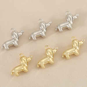 Macro shot of silver and gold dachshund charms with zirconia stones on silk fabric