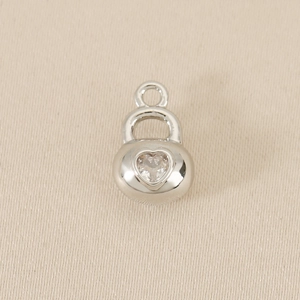Detailed view of silver heart pendant with sparkling zircon on silk background