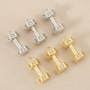 Macro shot of 18k gold-plated dumbbell charms featuring sparkling cubic zirconia stones