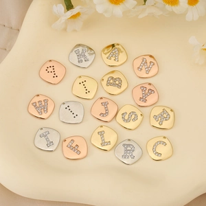 Vue détaillée de breloques alphabet DIY avec zircons en finitions or, argent et or rose