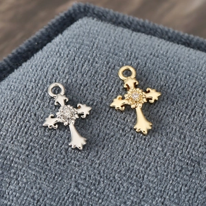 Macro shot of baroque 18K gold and silver cross pendants with shimmering zircon crystals
