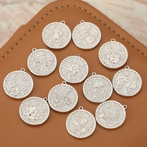 Macro detail of 12 silver-finish round floral charms on premium brown leather surface