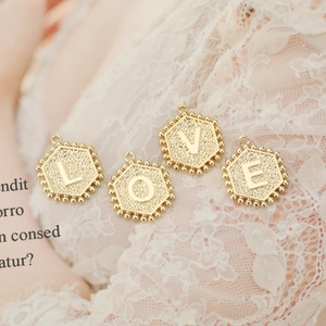 18K gold-plated hexagonal letter pendants forming LOVE on white lace background