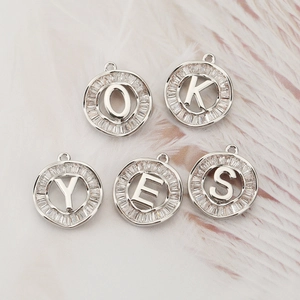 Five round 18K gold plated copper alphabet pendants with baguette-cut cubic zirconia insets