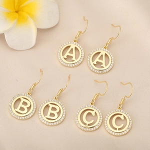 Detailed shot of three golden hook earrings with A, B, C letters and white cubic zirconia