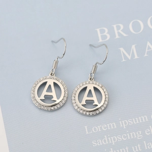 Detailed close-up of silver dangling earrings with diamond-encrusted letter A charm