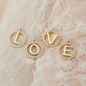 Detail of LOVE gold-plated pendants with micro-pave cubic zirconia on white lace background