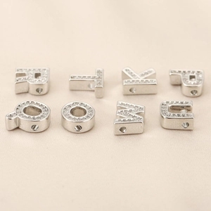 Macro shot of silver letters beads with micro-paved zircons for DIY jewelry making