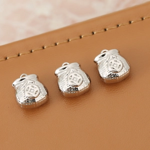 Macro detail of three silver lucky money bag pendants with embossed coin patterns on leather