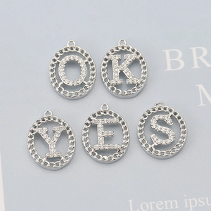 Macro detail of silver letter pendants O K Y E S with sparkling crystal pavé setting