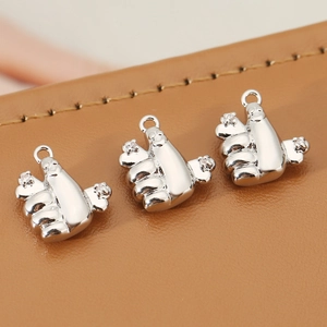 Close-up of polished silver thumb gesture pendants with small zircon stones for DIY jewelry