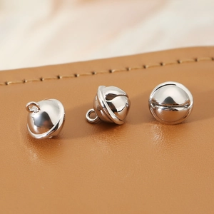 Close-up of three polished silver metal bell pendants for DIY jewelry making