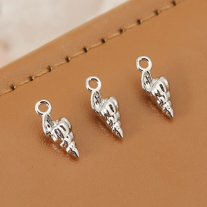 Detailed macro of silver conch charms for DIY jewelry making on brown leather background