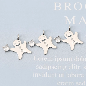 Détail de trois pendentifs bonhomme de pain d'épices sertis de zircons sur carte