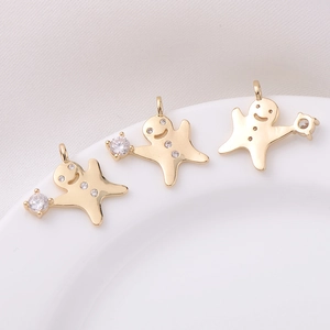 Trois pendentifs bonhomme de pain d'épices dorés 18K avec zircons sur fond blanc épuré