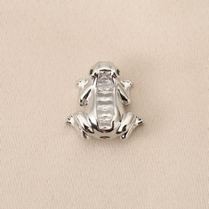 Détail d'un pendentif grenouille argenté avec cristaux et yeux noirs brillants