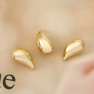 Drie minimalistische gouden druppelhangers met hoogglans spiegelafwerking op zachte stof